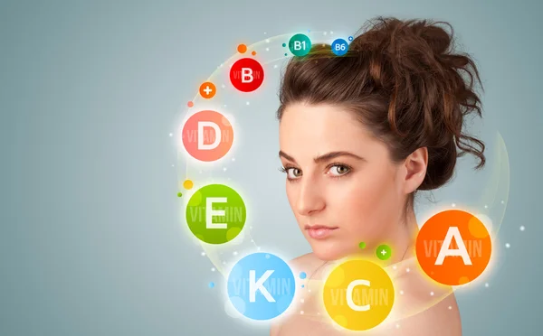 Pretty young girl with colorful vitamin icons and symbols — Stock Photo, Image