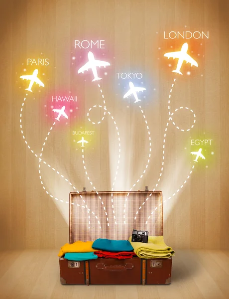 Travel bag with clothes and colorful planes flying out — Stock Photo, Image