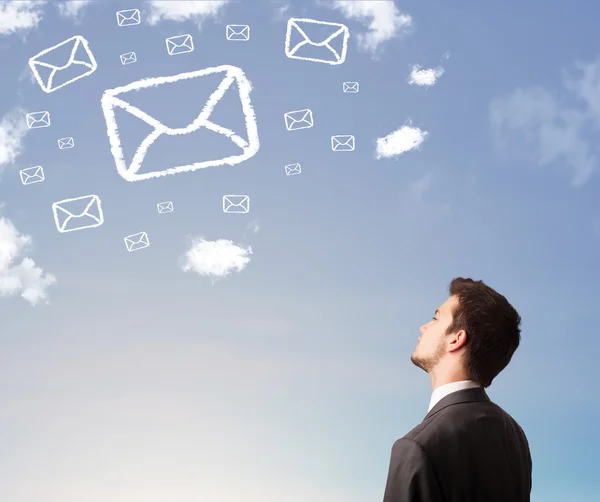 Businessman looking at mail symbol clouds on blue sky — Stock Photo, Image