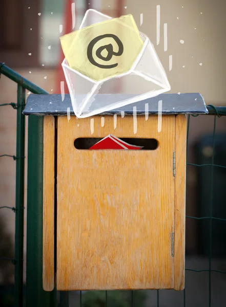 Envelope with email sign dropping into mailbox — Stock Photo, Image