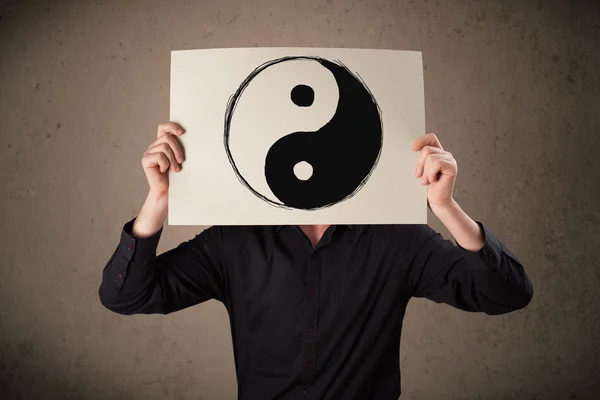 Businessman holding a paper with a yin-yang on it in front of hi — Stock Photo, Image