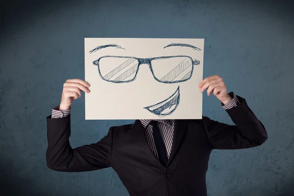Empresário segurando um papel com rosto sorridente na frente de sua hea — Fotografia de Stock