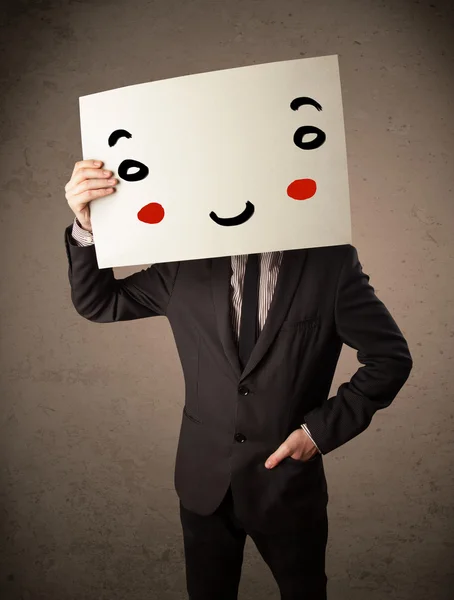 Businessman holding a cardboard with a smiley face on it — Stock Photo, Image