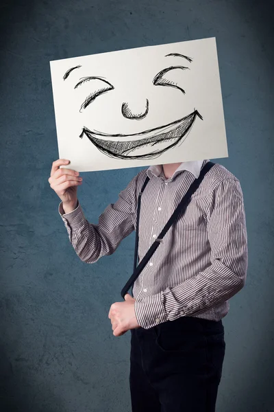 Empresário segurando um papel com rosto sorridente na frente de sua hea — Fotografia de Stock