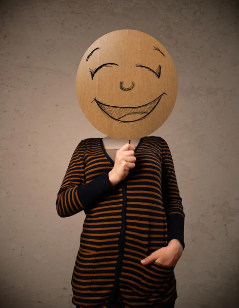 Young woman holding a smiley face board — Stock Photo, Image