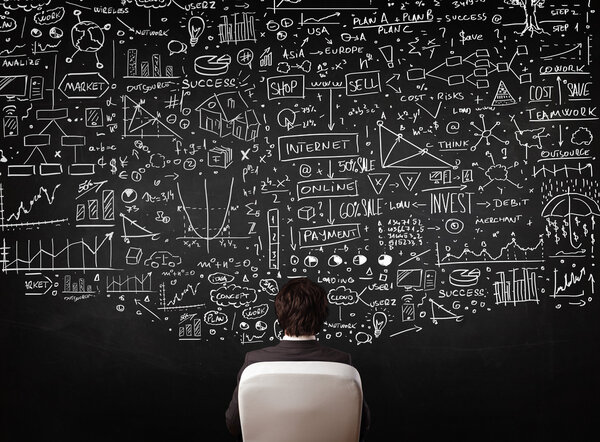 Бизнесмен сидит перед доской с картами