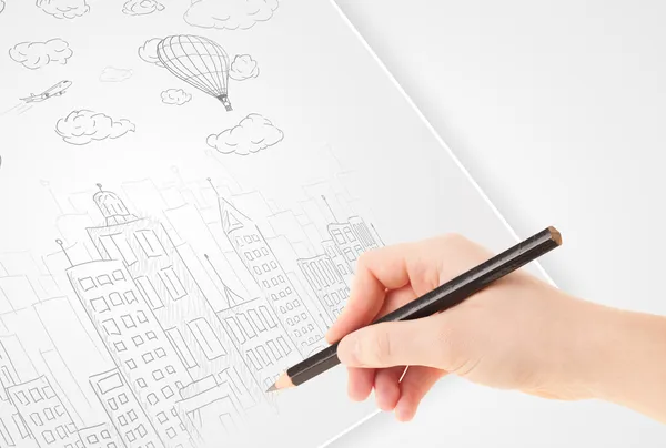 A person drawing sketch of a city with balloons and clouds on a — Stock Photo, Image