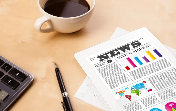 Tablet pc shows news on screen with a cup of coffee on a desk — Stock Photo, Image