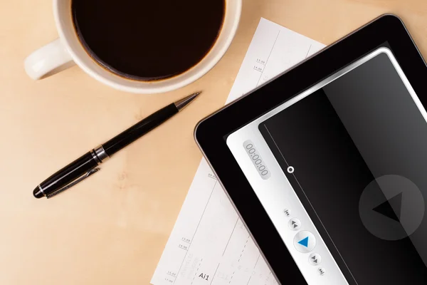 Tablet pc showing media player on screen with a cup of coffee on — Stock Photo, Image