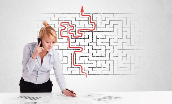 Business woman at desk with labyrinth and arrow — Stock Photo, Image