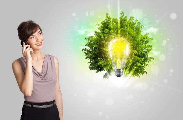 Fiatal lány bemutató ötlet villanykörte zöld fa — Stock Fotó