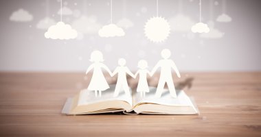 Ailenin karton figürleri açık bir kitabın üzerinde.
