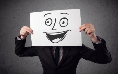 empresario sosteniendo una cartulina con cara sonriente en él en frente 