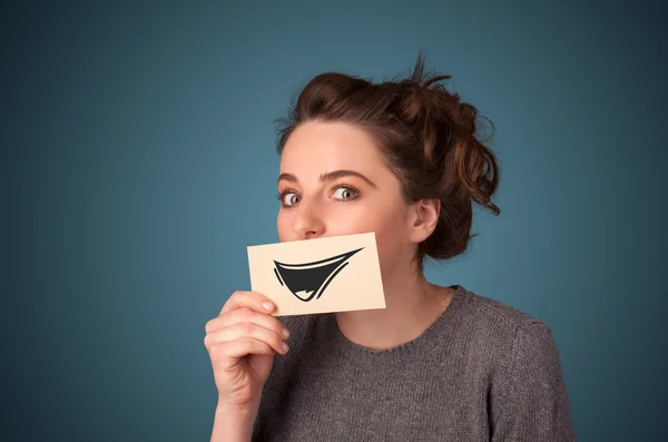 Happy cute girl holding paper with funny smiley drawing — Stock Photo, Image