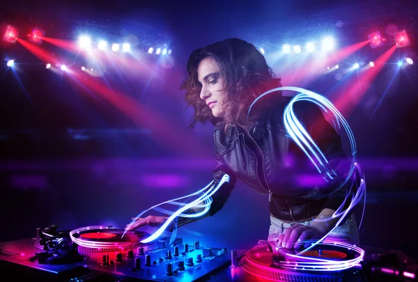 Disc jockey girl playing music with light beam effects on stage — Stock Photo, Image