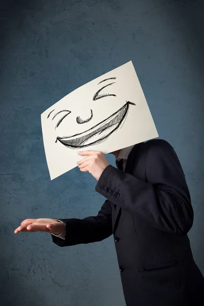 Businessman holding a paper with smiley face in front of his hea — Stock Photo, Image