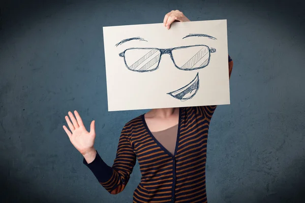 Mujer sosteniendo un papel con la cara sonriente delante de su cabeza — Foto de Stock