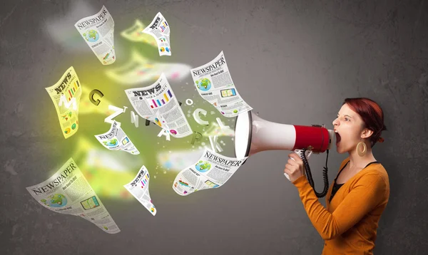 Girl yelling into loudspeaker and newspapers fly out — Stock Photo, Image