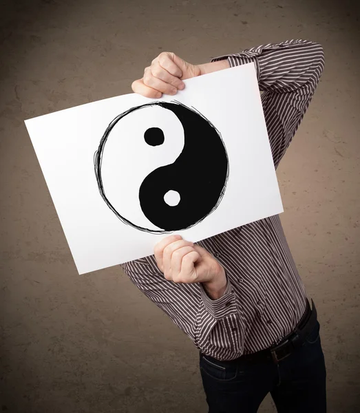 Businessman holding a paper with a yin-yang on it in front of hi — Stock Photo, Image