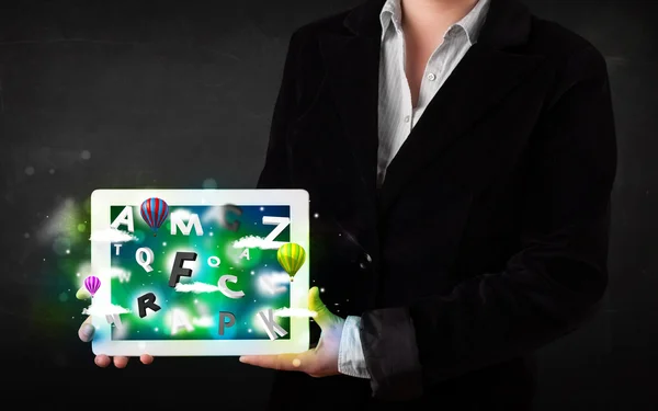 Young person showing tablet with abstract letters and sky — Stock Photo, Image