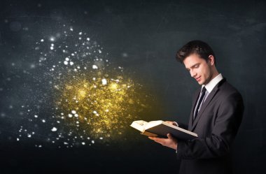 Genç adam sihirli bir kitap okuyor.