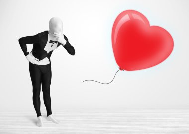 Morpsuit giyip balon şeklinde bir kalbe bakan yakışıklı bir adam.