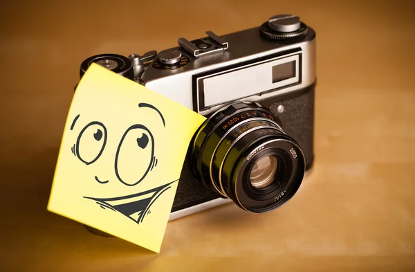 Post-it note with smiley face sticked on photo camera — Stock Photo, Image