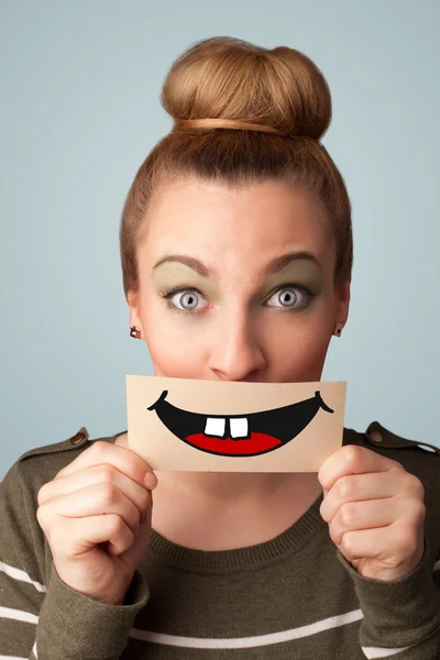 Happy pretty woman holding card with funny smiley — Stock Photo, Image