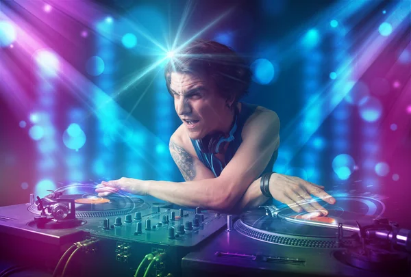 Ди-джей смешивает музыку в клубе с синими и фиолетовыми огнями — стоковое фото