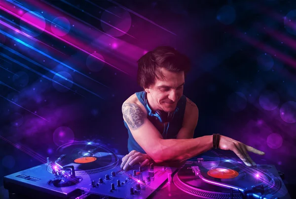 Young DJ playing on turntables with color light effects — Stock Photo, Image