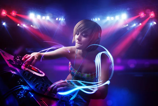 Disc jockey girl playing music with light beam effects on stage — Stock Photo, Image