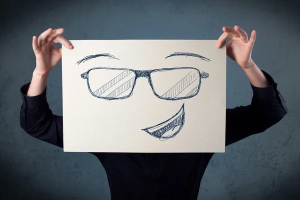 Businessman holding a paper with smiley face in front of his hea — Stock Photo, Image