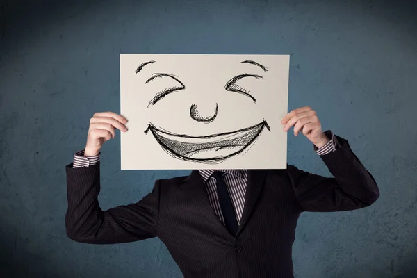 Empresário segurando um papel com rosto sorridente na frente de sua hea — Fotografia de Stock