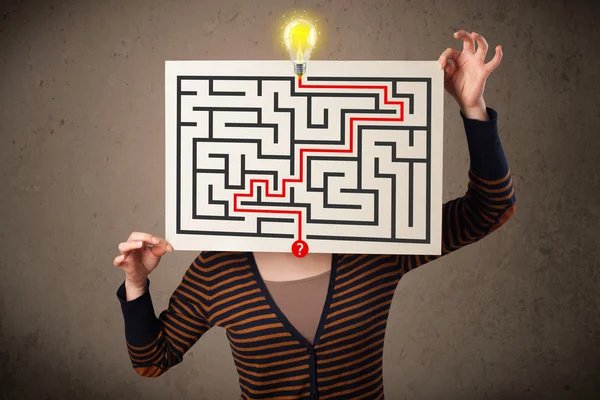 Woman holding a paper with a labyrinth on it in front of her hea — Stock Photo, Image