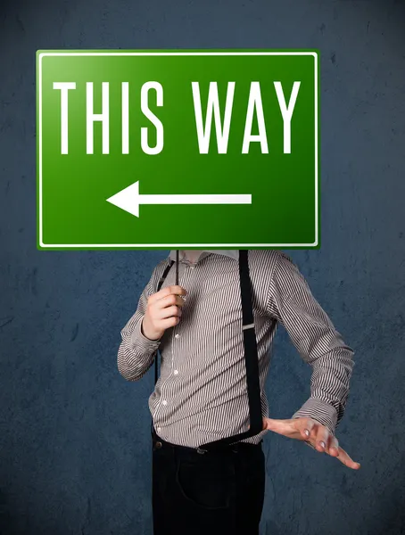 Businessman holding a direction sign — Stock Photo, Image