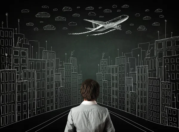 Businessman sitting in front of a cityscape drawing on a chalkbo — Stock Photo, Image