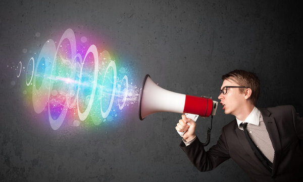 Man yells into a loudspeaker and colorful energy beam comes out