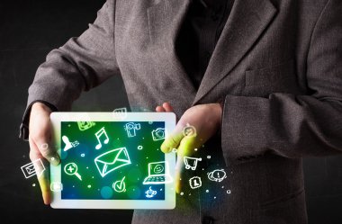 Medya simgeleri ve sembolleri olan bir tablet tutan kişi