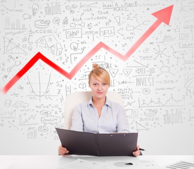 Piyasa diyagramlarıyla masada oturan iş kadını. 