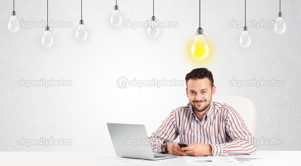 Business man sitting at table with idea light bulbs