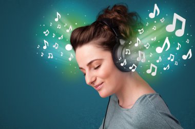 Kulaklıklı genç bir kadın müzik dinliyor.