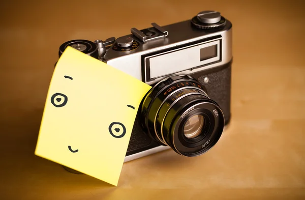 Nota post-it con la cara sonriente pegada a una cámara fotográfica — Foto de Stock