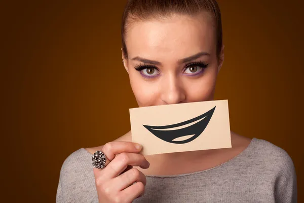 Happy pretty woman holding card with funny smiley — Stock Photo, Image