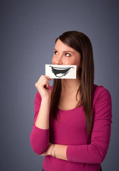 Feliz linda chica sosteniendo papel con divertido dibujo sonriente — Foto de Stock