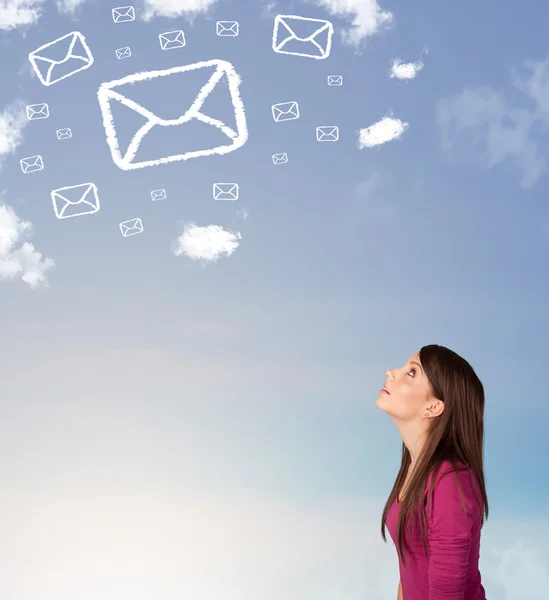 Chica joven mirando el símbolo de correo nubes en el cielo azul — Foto de Stock