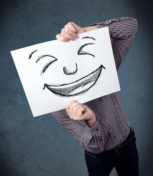 Empresário segurando um papel com rosto sorridente na frente de sua hea — Fotografia de Stock