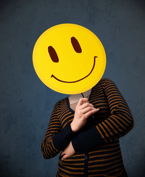 Young woman holding a smiley face emoticon — Stock Photo, Image