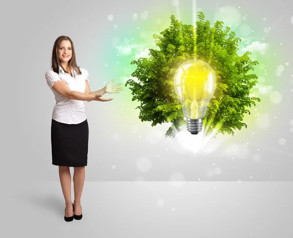 Giovane ragazza che presenta idea lampadina con albero verde — Foto Stock