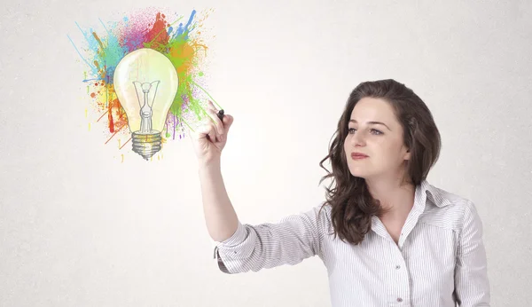 Jovem senhora desenhando uma lâmpada colorida com salpicos coloridos — Fotografia de Stock