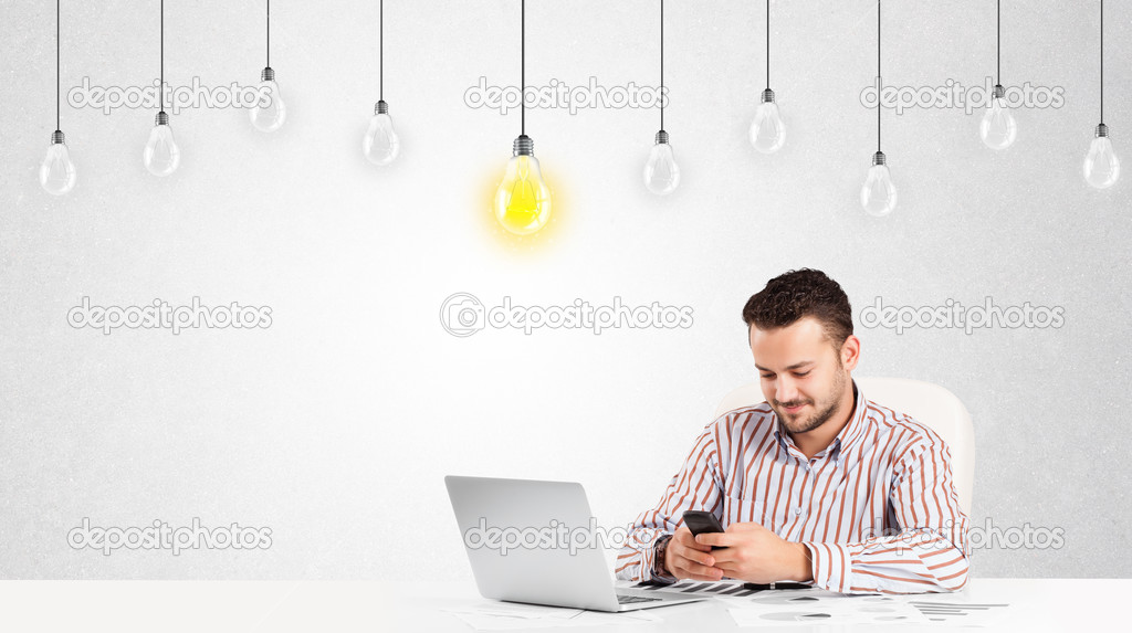 Business man sitting at table with idea light bulbs